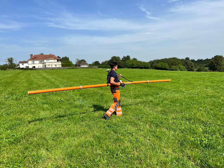 GEOTEC surveyor carrying CMD electromagnetic conductivity equipment across a field